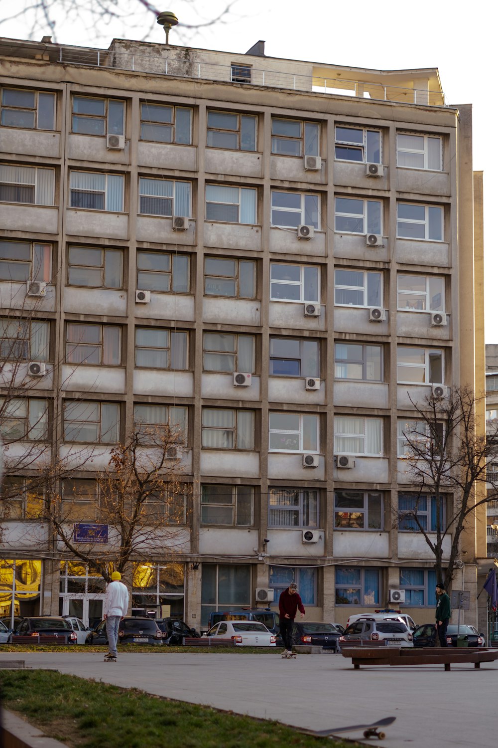 a tall building with lots of windows next to a park