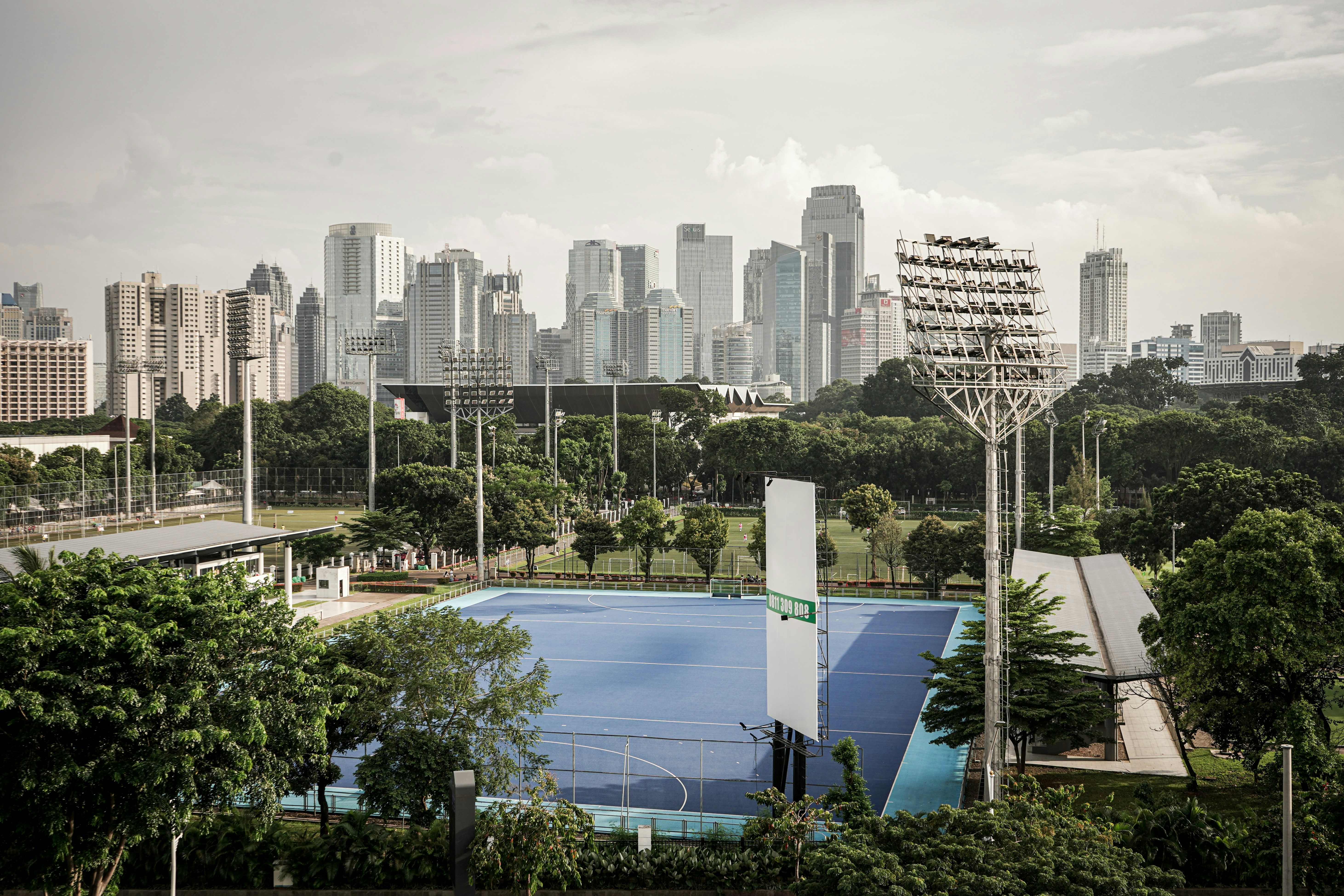 a tennis court surrounded by trees with a city in the background