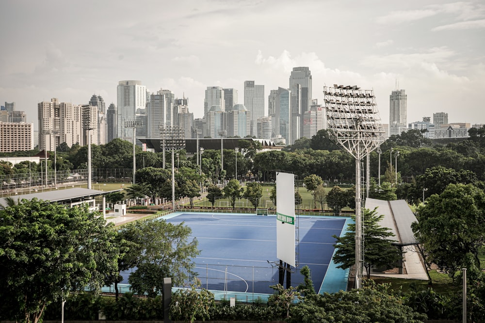 a tennis court surrounded by trees with a city in the background