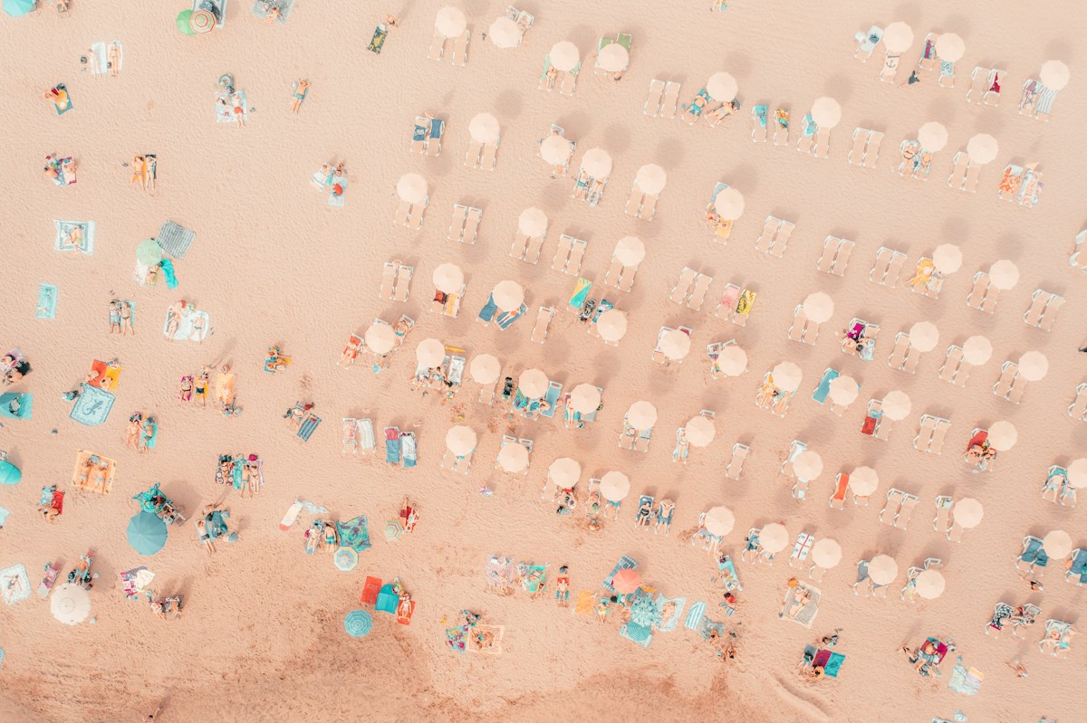 Aerial view of a beach with colorful umbrellas and chairs, illustrating a well-organized summer swim team gathering.