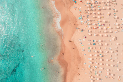 an aerial view of a beach with umbrellas and chairs