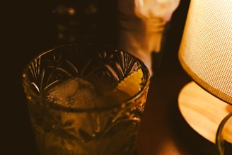 a close up of a glass next to a lamp