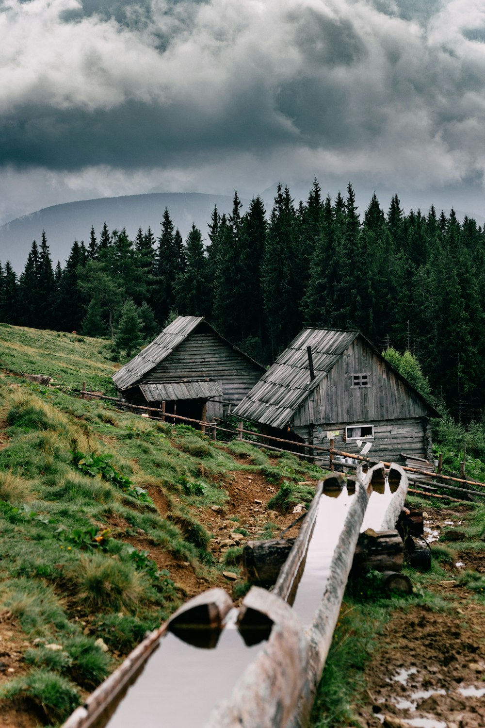 a wooden house sitting on top of a lush green hillside