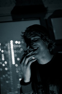 A candid photo of a person laughing outdoors with blurred cityscape background.