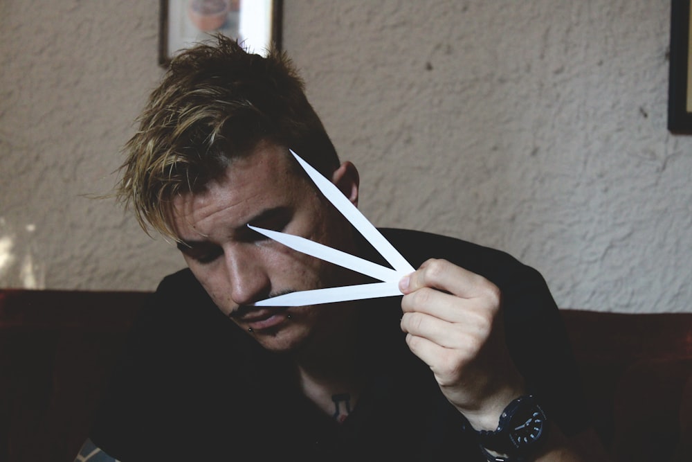 a man holding a pair of scissors over his face