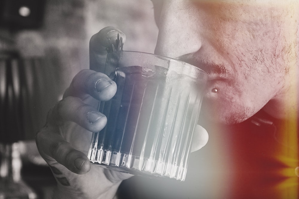 a man holding a glass with a liquid inside of it