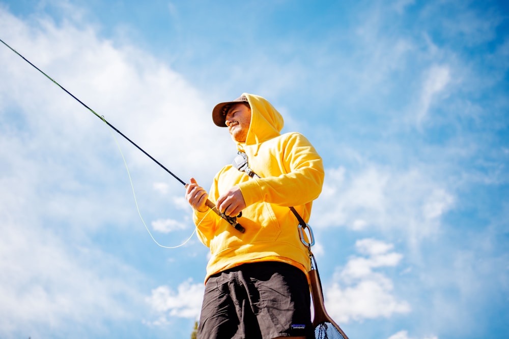 a man in a yellow jacket holding a fishing pole