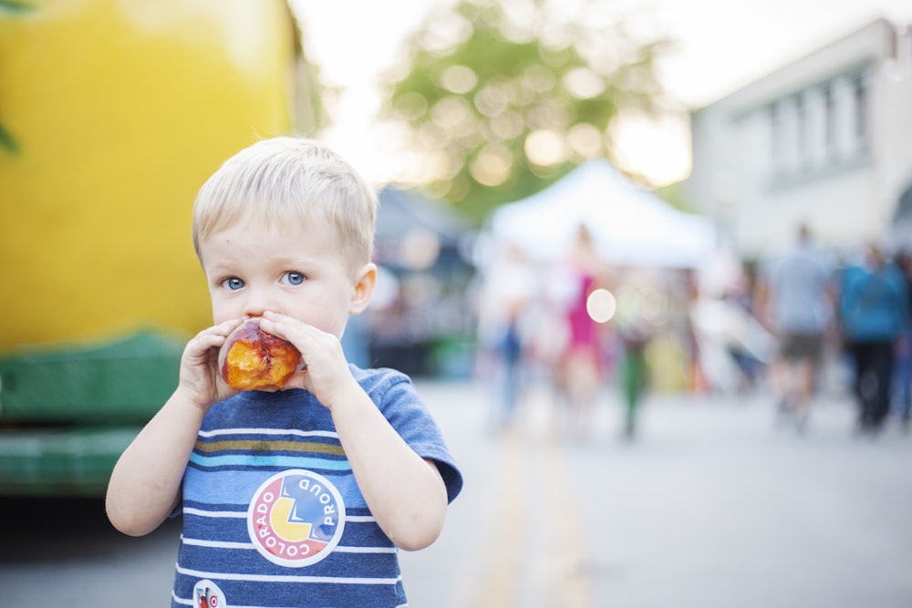 a little boy eating a piece of food