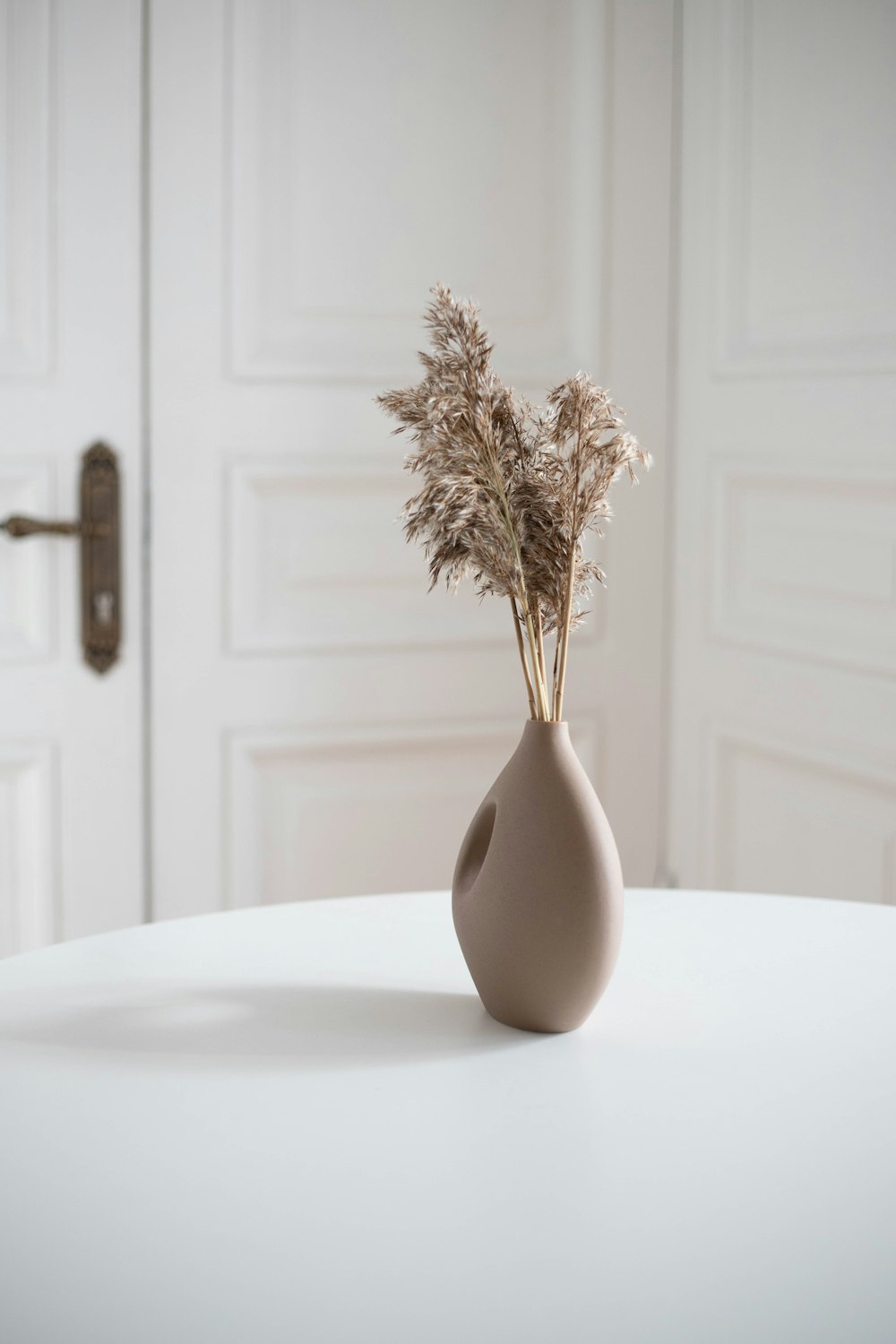 a vase with dried flowers in it sitting on a table