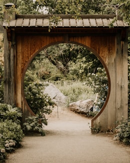 a wooden arch in a garden with a path leading to it