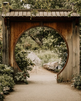 a wooden arch in a garden with a path leading to it