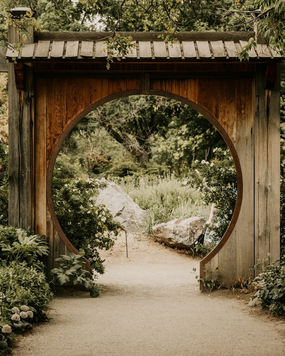 a wooden arch in a garden with a path leading to it