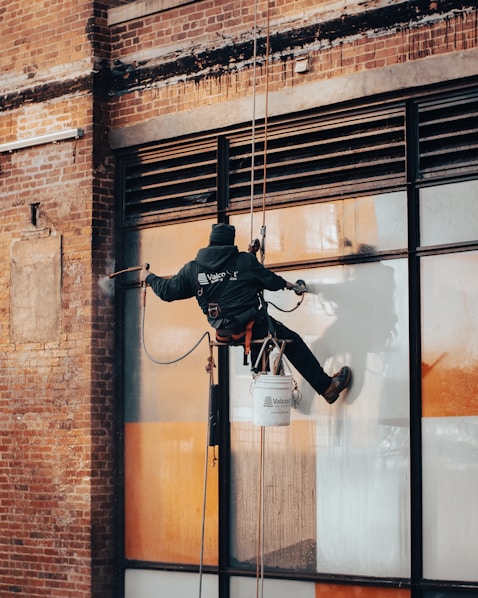 Technician washing large glass windows on a commercial building.