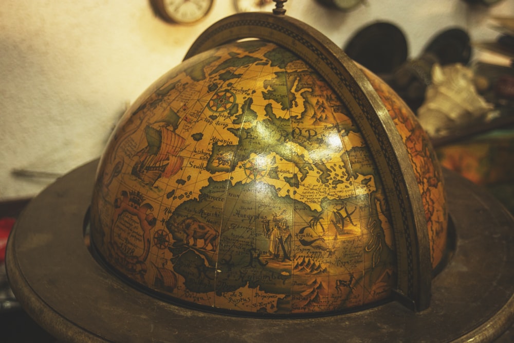 a globe on a stand with a clock in the background