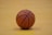 A close-up of a basketball resting on a wooden gym floor.