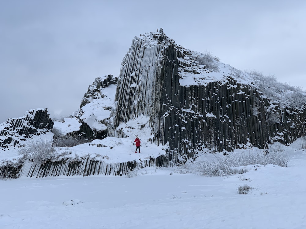 a person standing in front of a tall rock formation