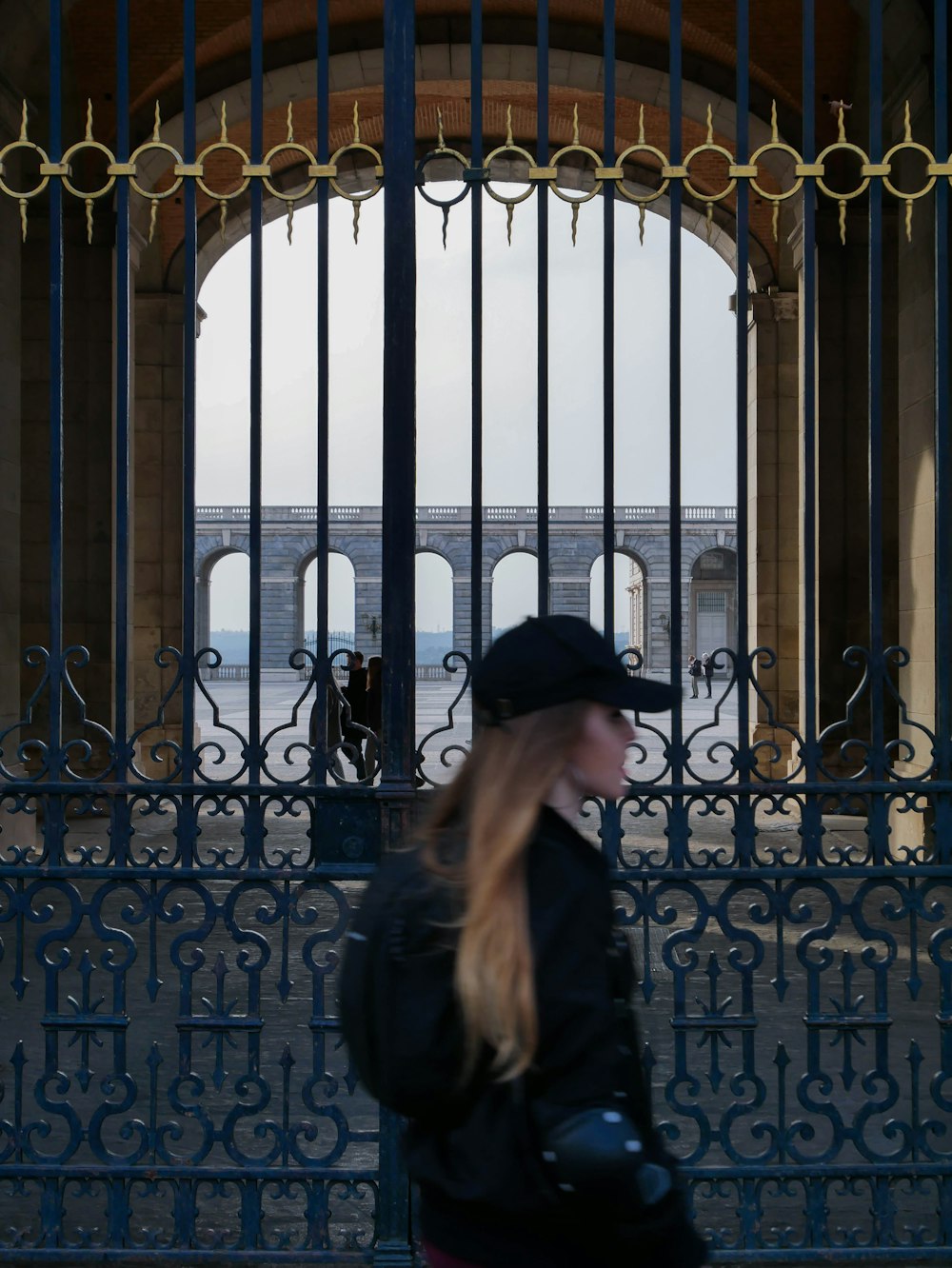 a woman in a black hat is walking by a gate