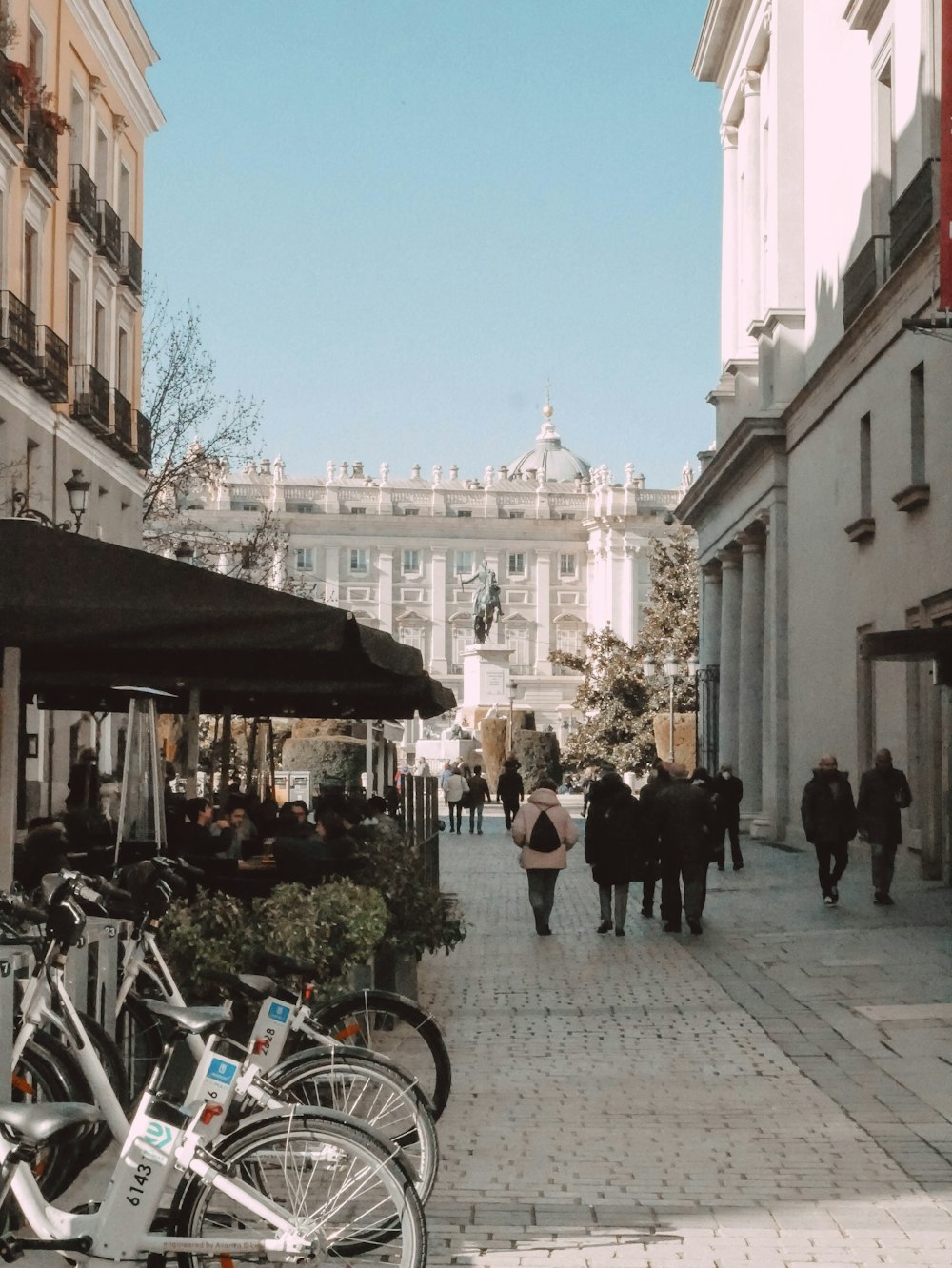 a group of people walking down a street next to tall buildings