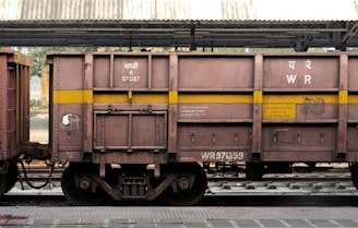 a train car sitting on the tracks under a bridge