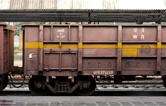 a train car sitting on the tracks under a bridge