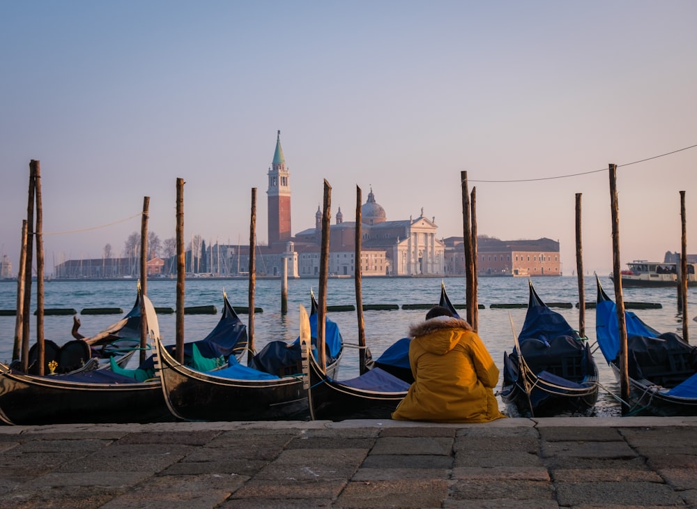 una fila di gondole sedute accanto a uno specchio d'acqua