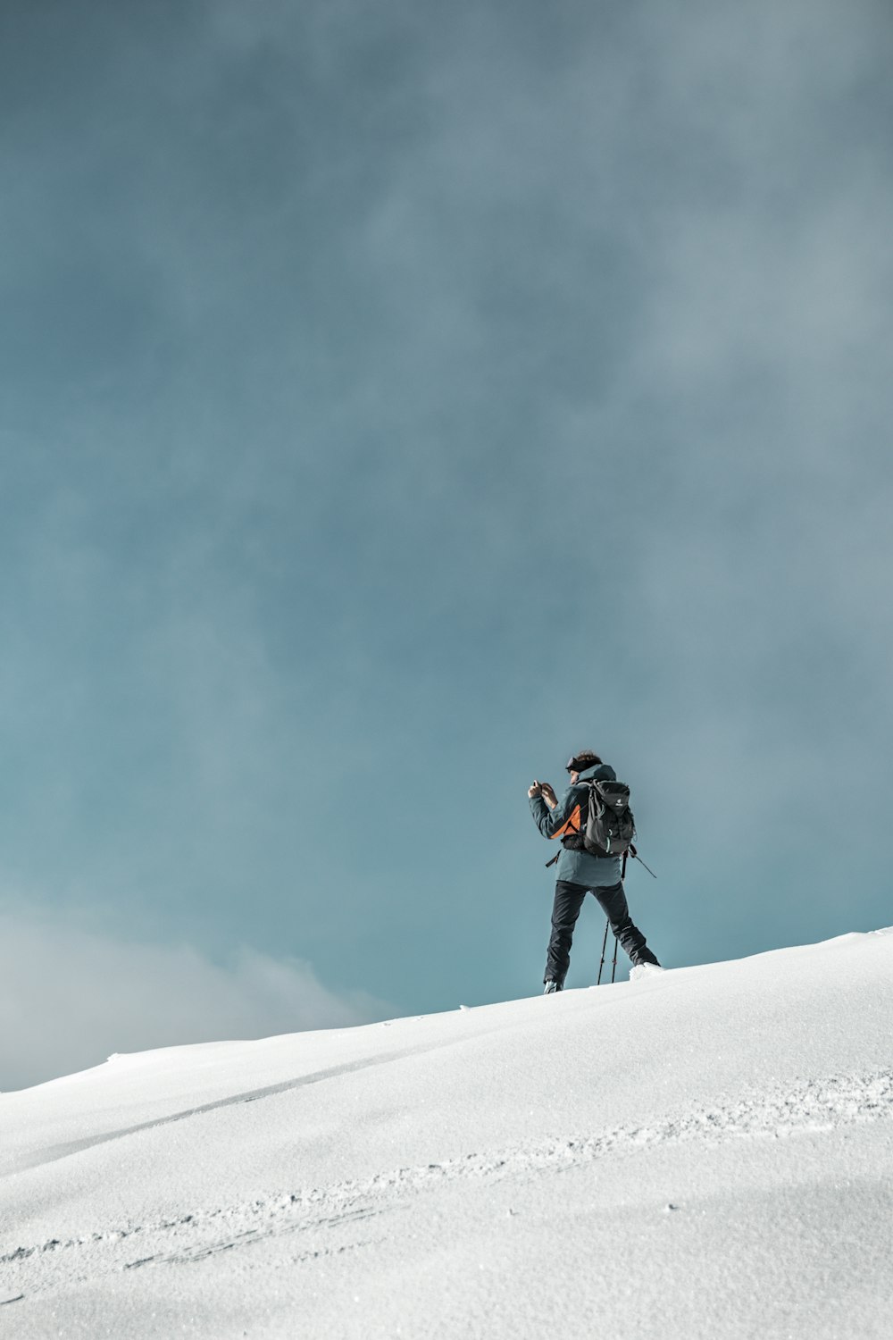 a person with a backpack and skis walking up a snowy hill