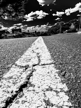 A cracked and potholed city street in Upland under a cloudy sky.