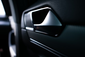 Close-up of a sleek automotive door handle being assembled in a modern factory.