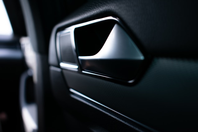 Close-up of a sleek automotive door handle being assembled in a modern factory.