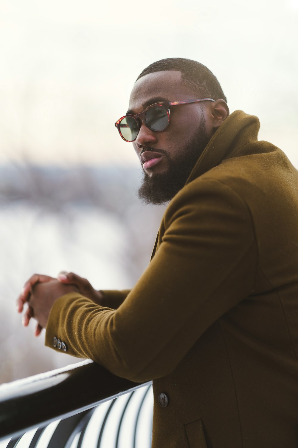 a man with a beard and glasses leaning on a rail