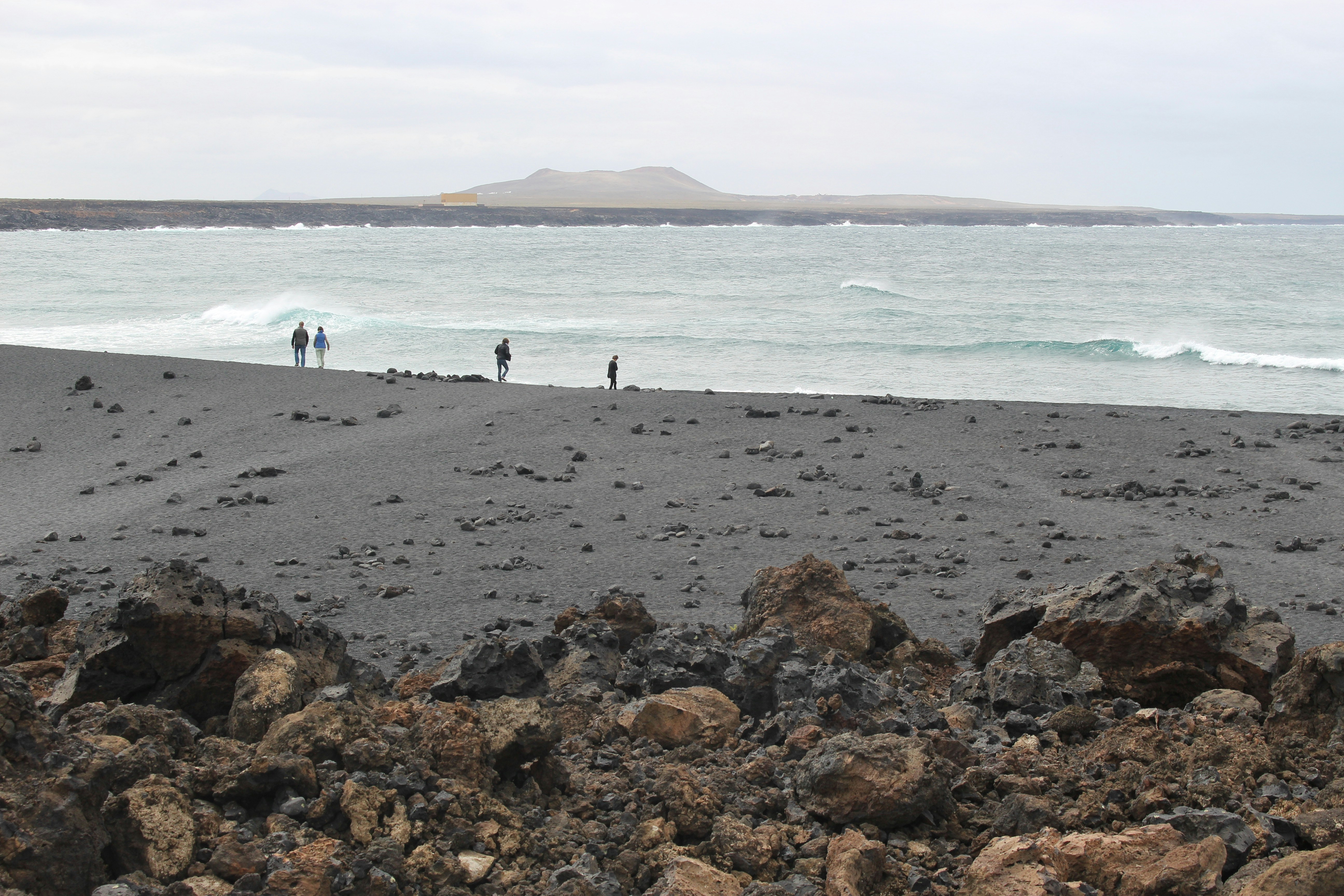 The beach Playa de Janubio on Southwest Lanzarote. People are strolling along the seashore. Canary Islands, Spain.