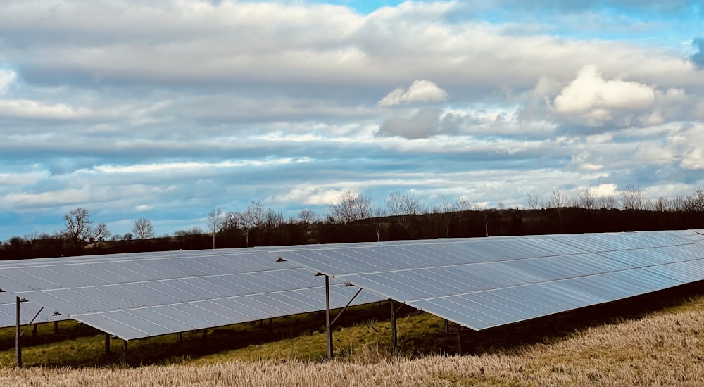 a row of solar panels sitting on top of a dry grass field