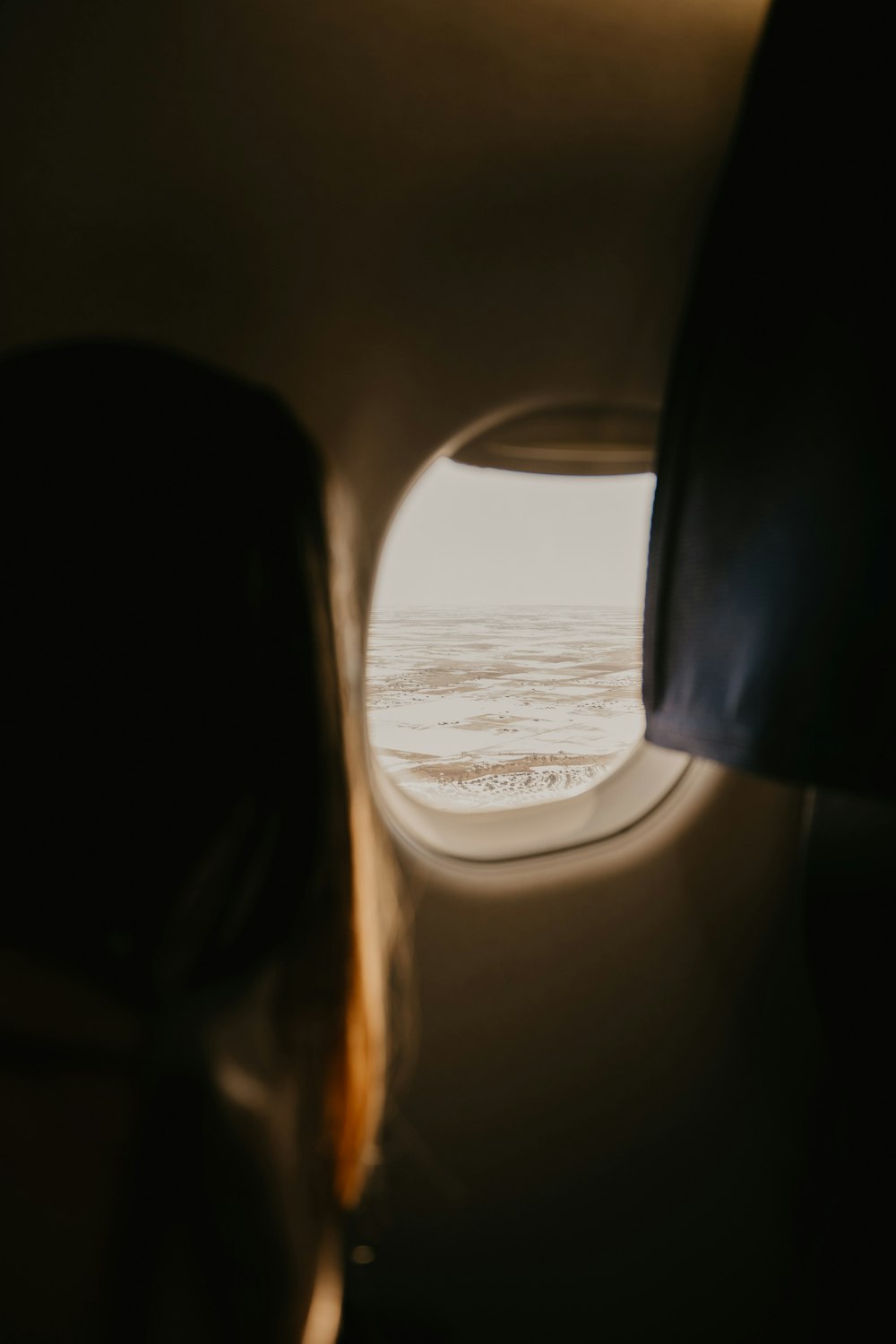 a woman looking out an airplane window at the ocean