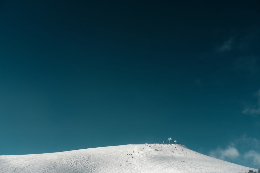 uma colina coberta de neve com um fundo do céu