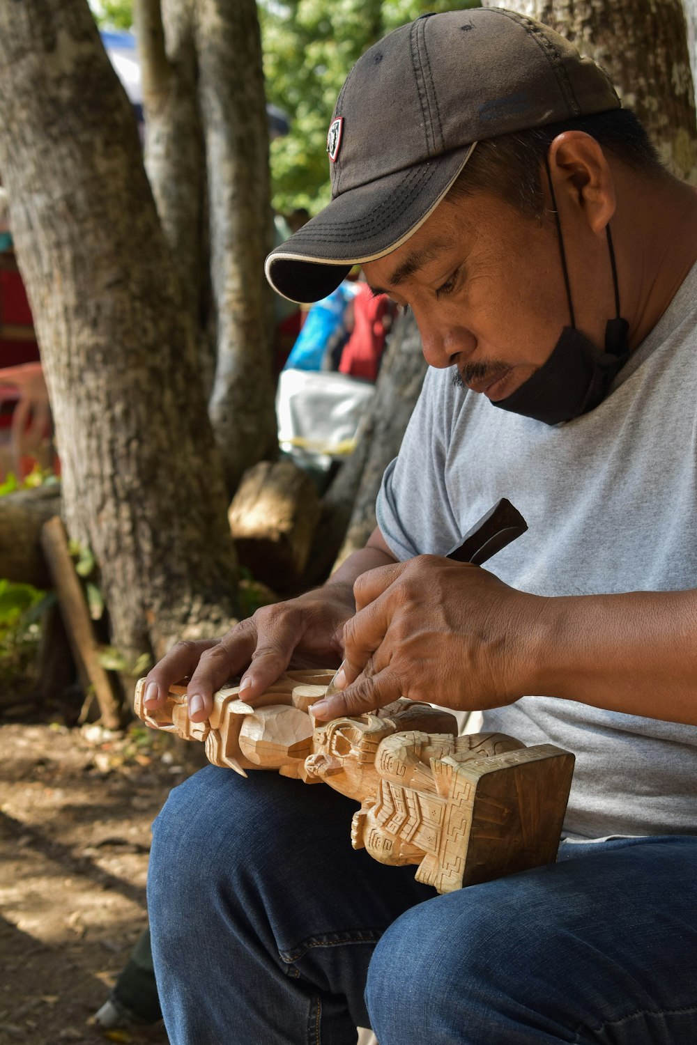 a man sitting on a bench carving a piece of wood