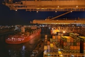 Cargo ship loaded with containers leaving a bustling port at dawn, symbolizing global trade.