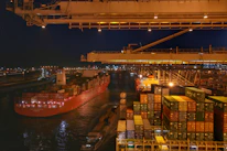 Close-up of a cargo ship being loaded at a bustling port.