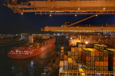 A dynamic scene of freight trucks and container terminals illuminated with blue and cyan lighting.