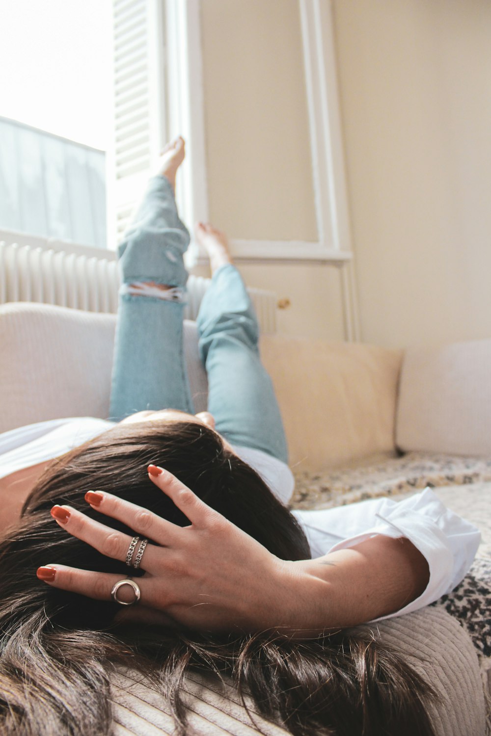 a woman laying on a bed with her hands on her head