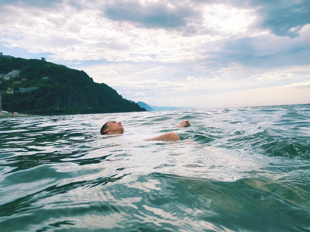 a man swimming in the ocean on a cloudy day