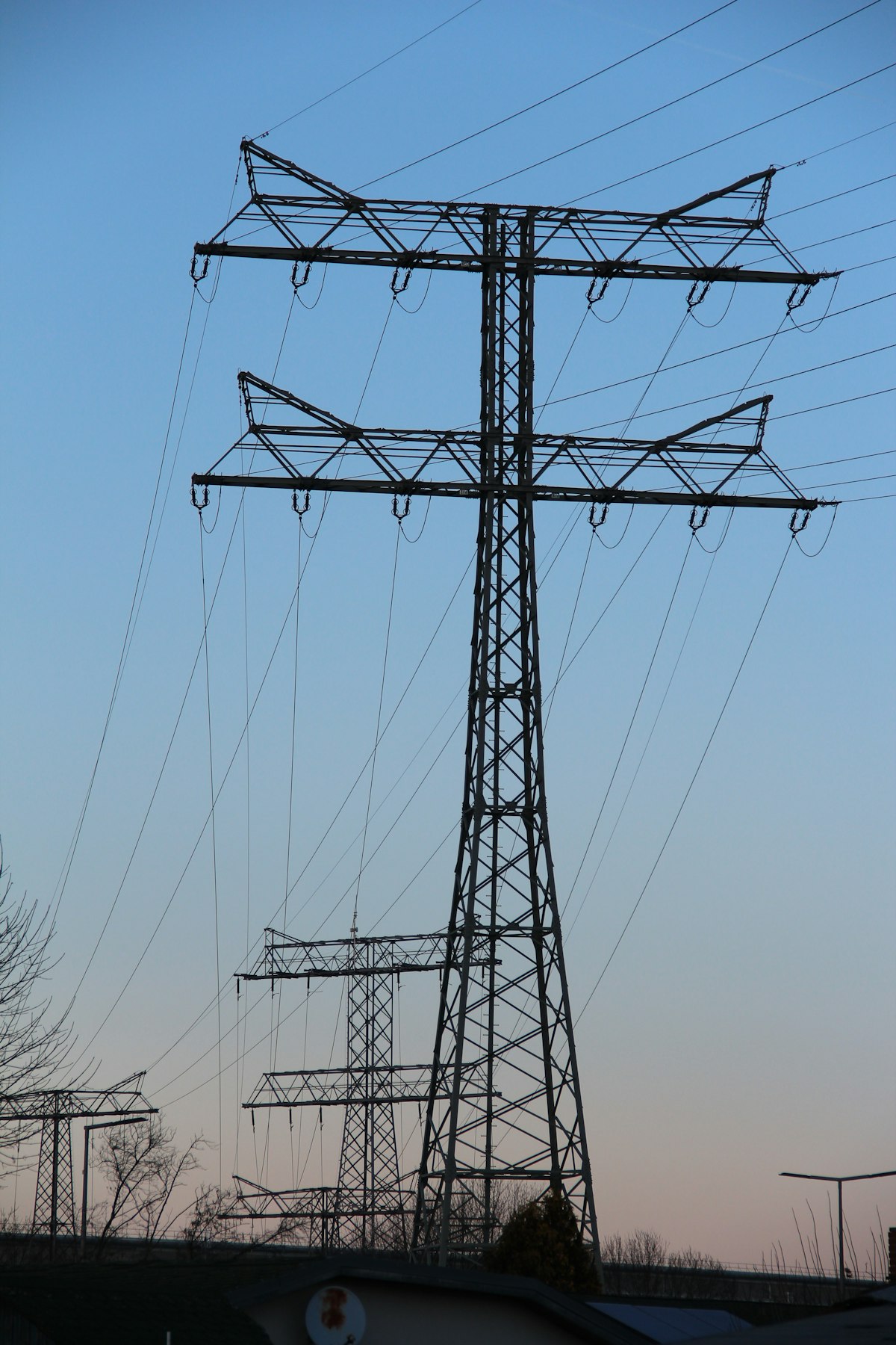 A tall high-voltage power transmission tower with multiple power lines extending against a clear sky
