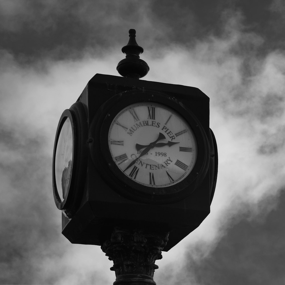 a black and white photo of a clock on a pole