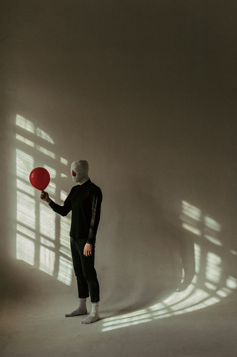 Ein Mann in weißer Maske hält einen roten Frisbee