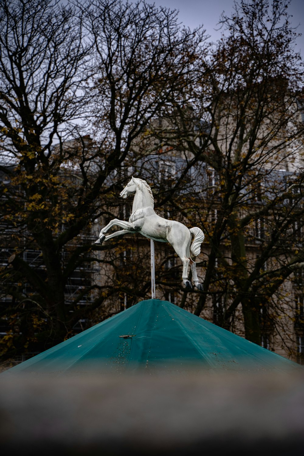 Une statue de cheval blanc au sommet d’un toit vert