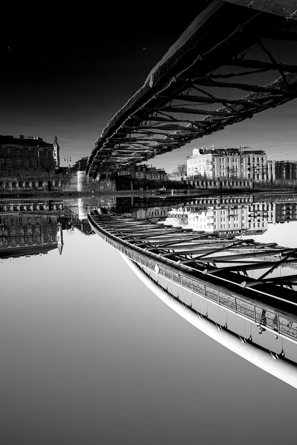 a black and white photo of a bridge over water