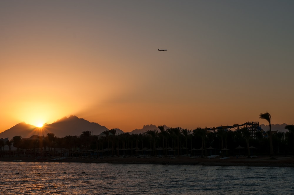 a plane flying over a body of water at sunset