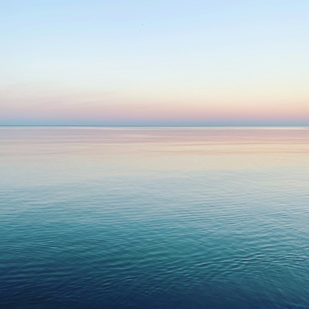 a large body of water sitting under a blue sky