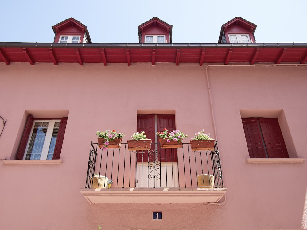 a pink building with two balconies and flowers on the balconies