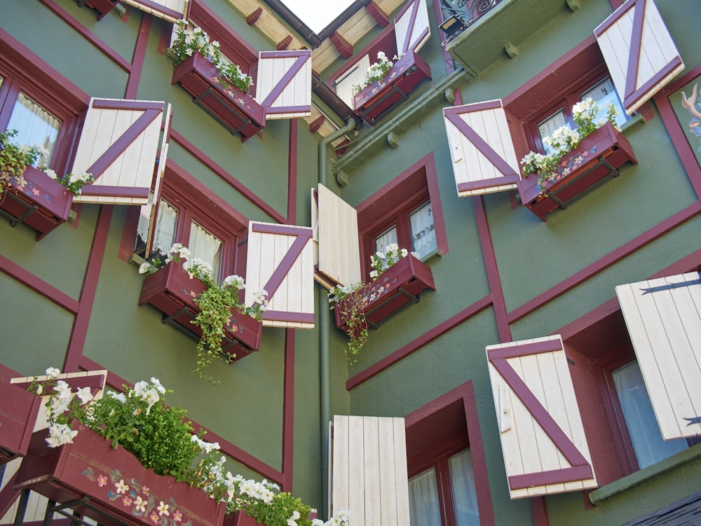 a green building with red and white shutters and windows