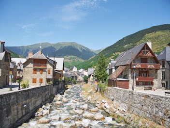 a river running through a small town surrounded by mountains